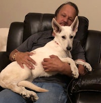 a man sitting in a chair with a white dog