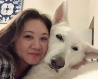 a woman is posing with a white dog