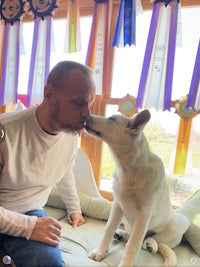 a man kissing a white dog